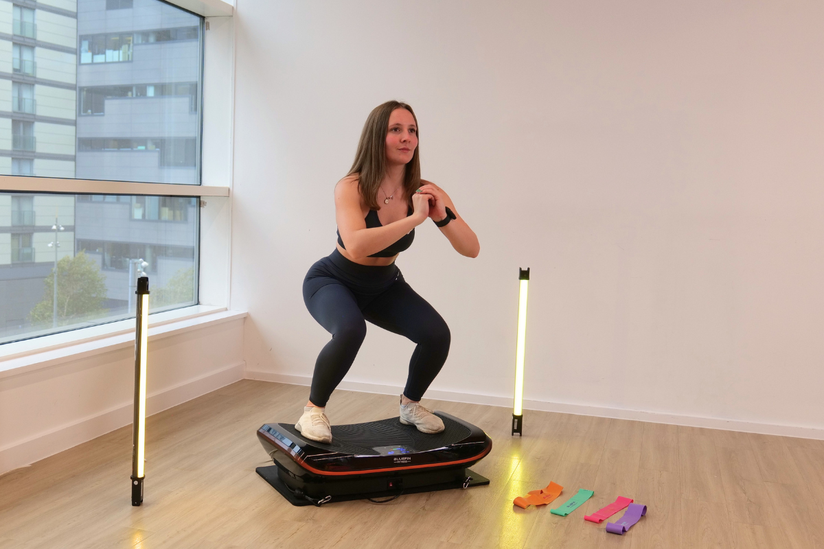 a woman doing a squat on a vibration plate