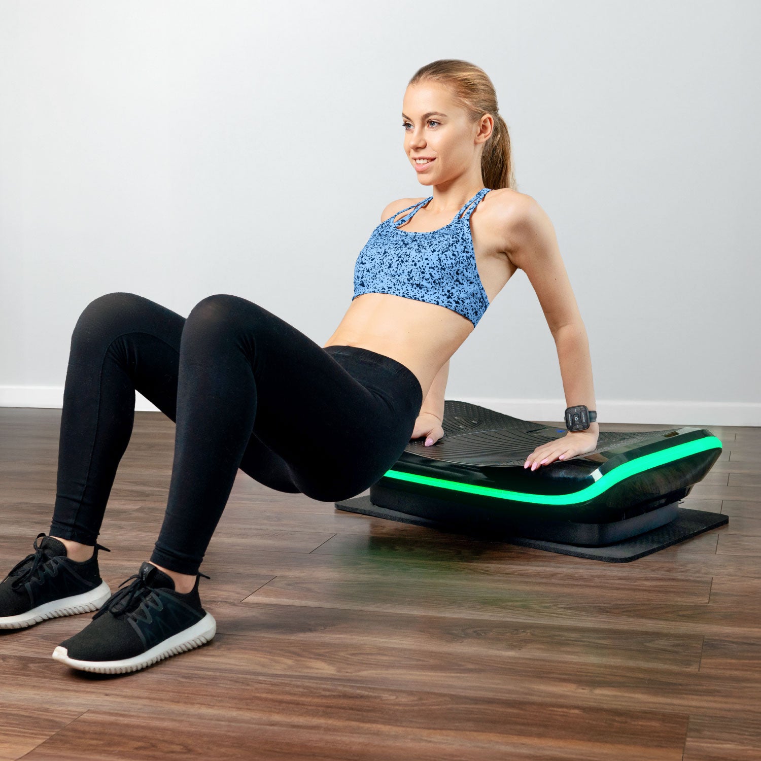 Woman in a blue sports bra and black leggings performing dips on a fitness platform with green lights.