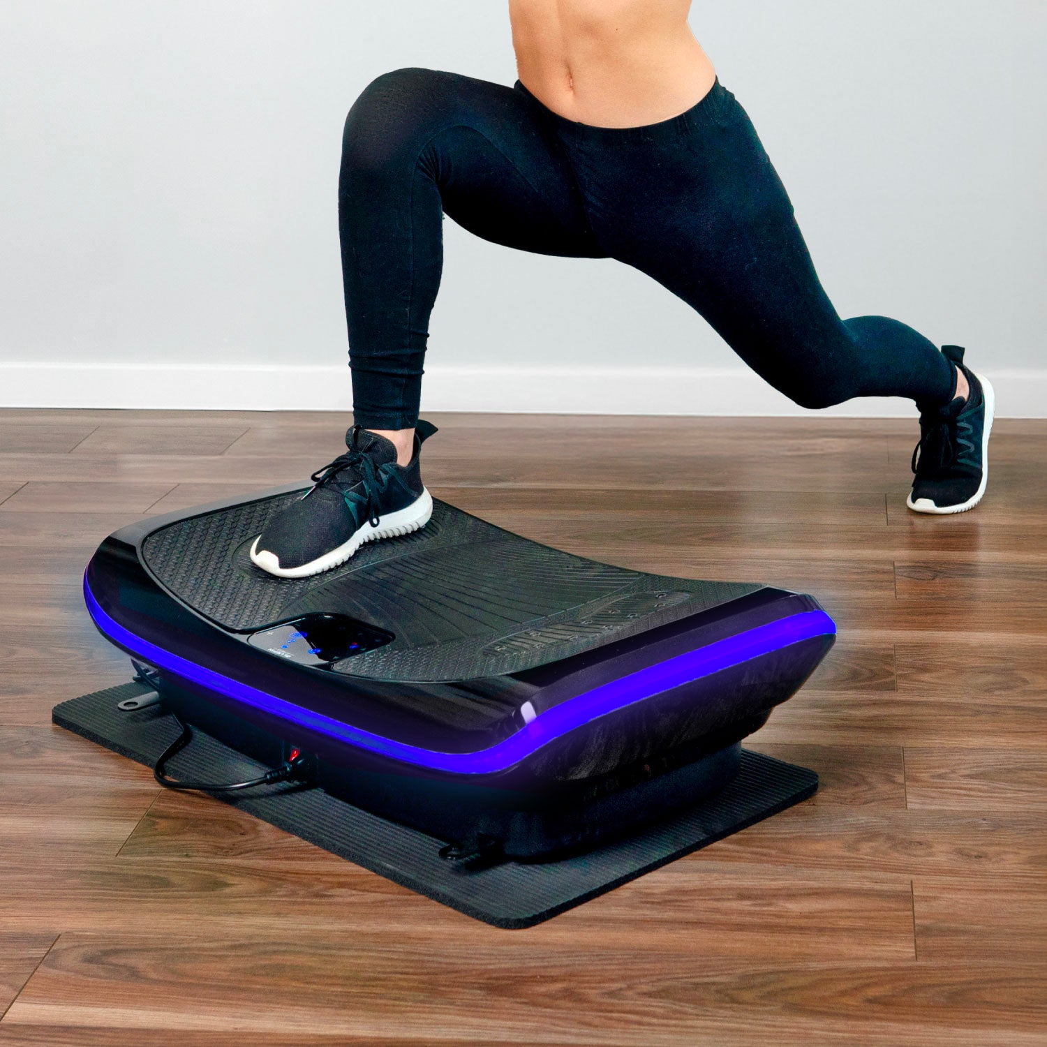 Person performing a lunge on a curved balance board with blue LED lights on the edge.