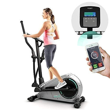 Woman exercising on an elliptical machine with a digital display and smartphone app integration.